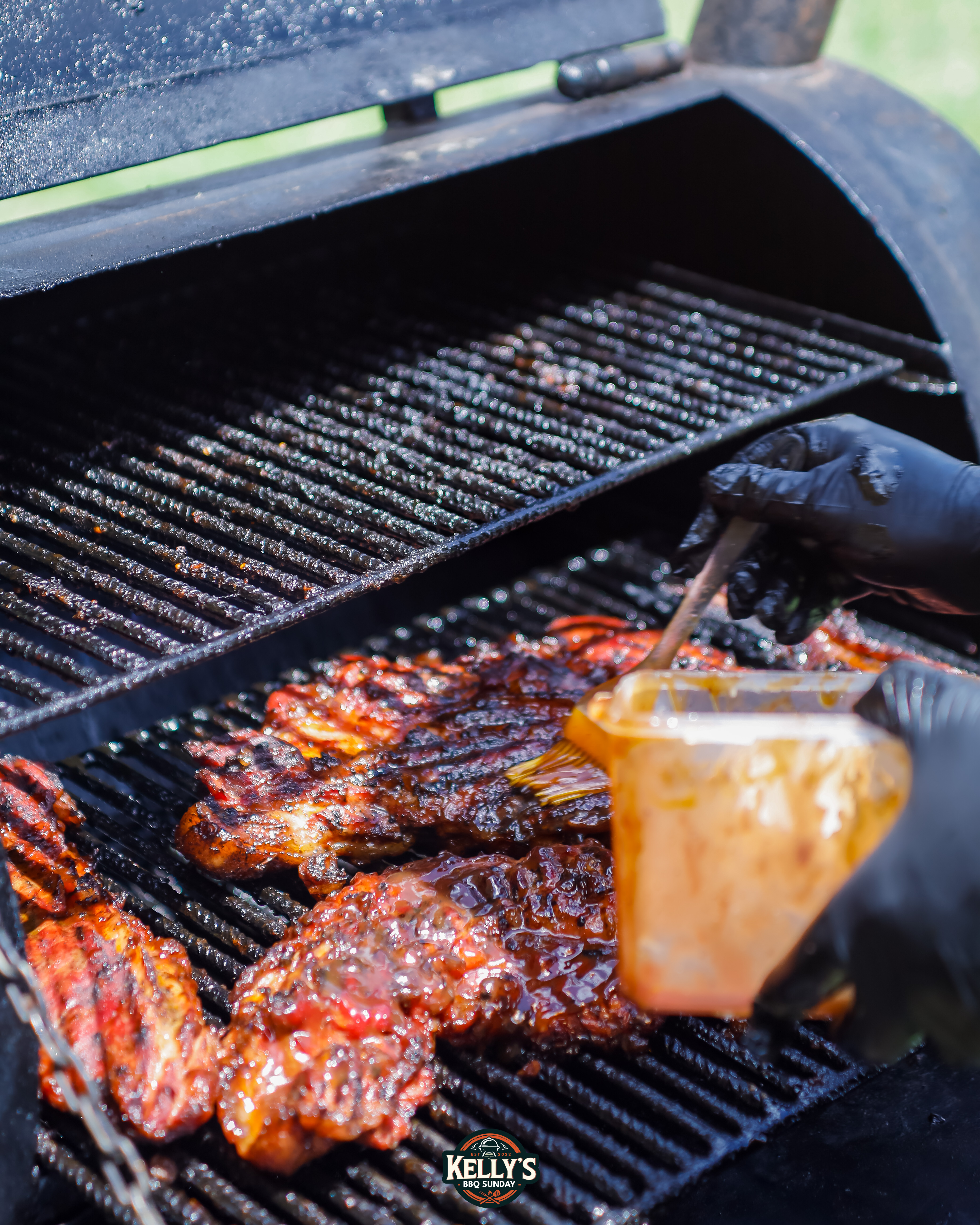 BBQ ribs being basted with sauce on a smoker grill