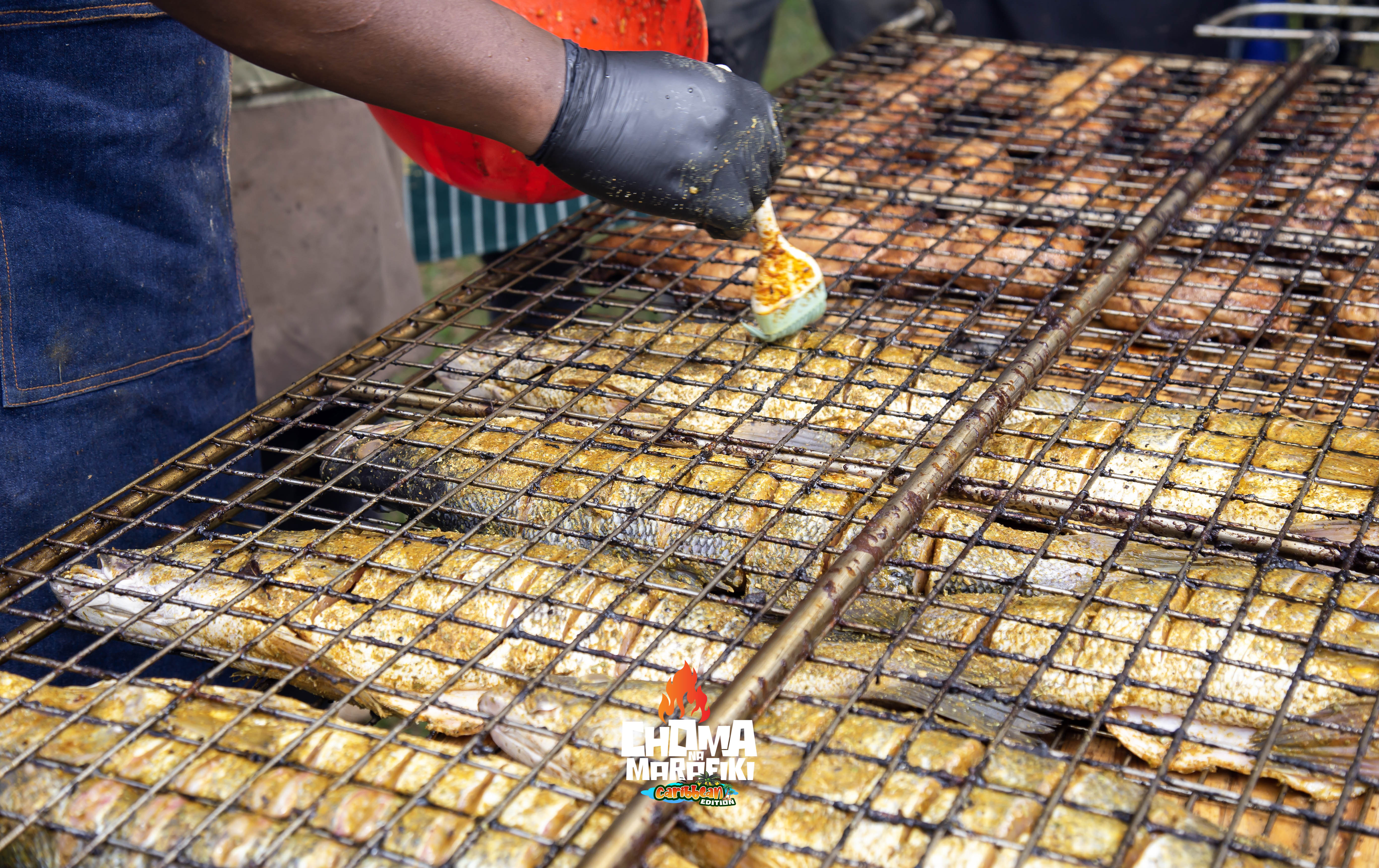 Whole fish grilling on large wire grill at Choma Na Marafiki Caribbean Edition